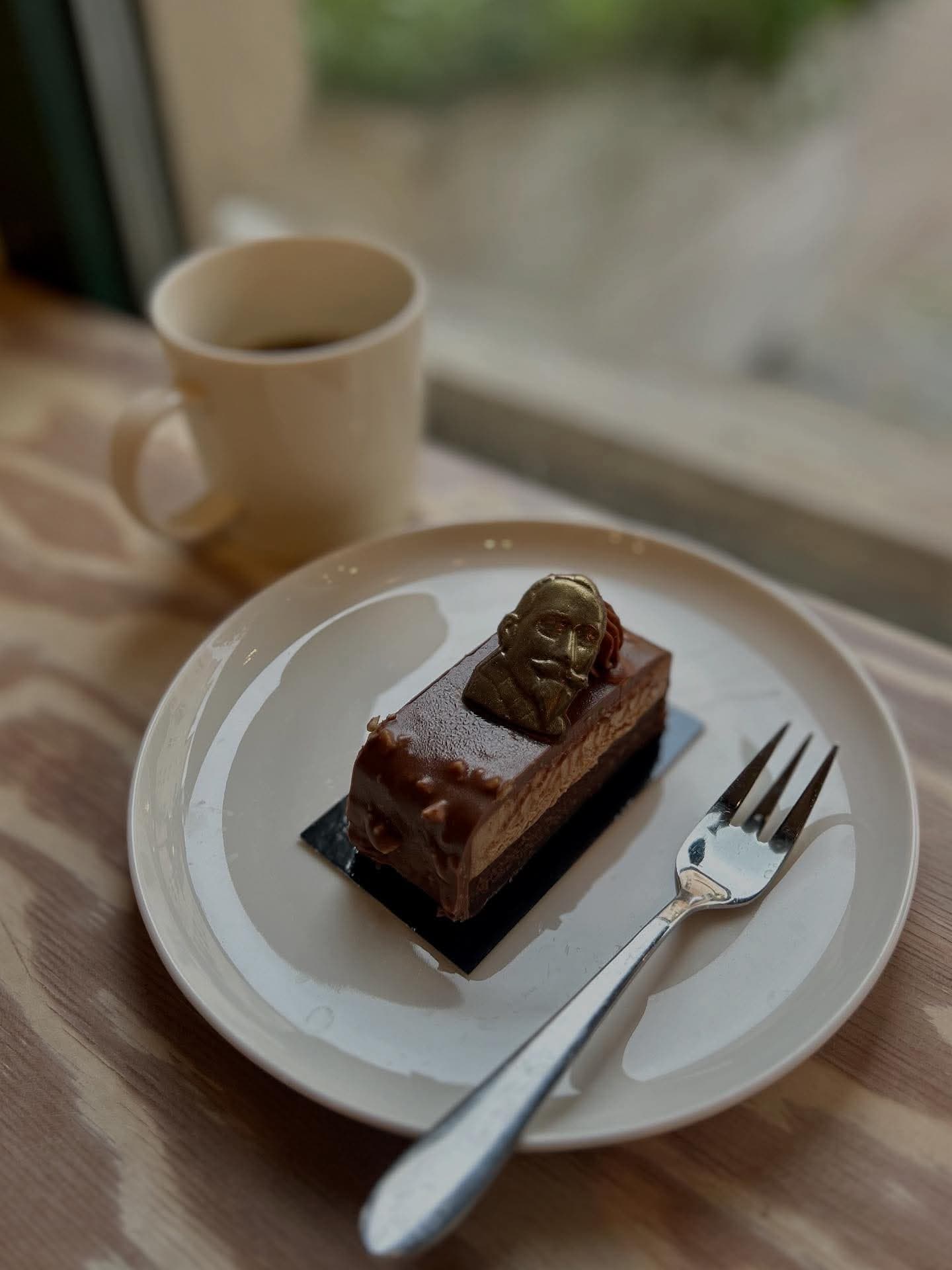 Chokladbit med gulddekor och en kopp kaffe